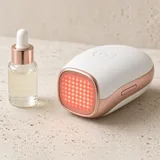 Illustration of a compact handheld red light device beside a serum bottle